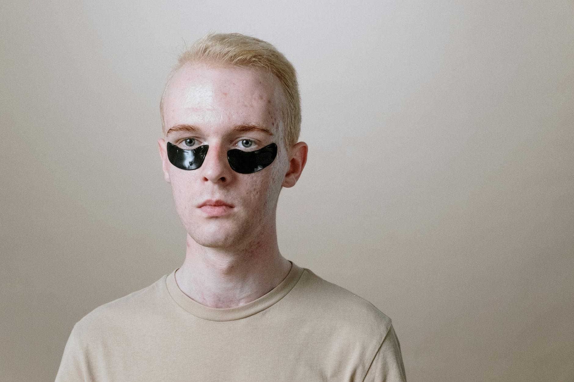 Portrait of a young man wearing under-eye patches, focusing on skincare and self-care routine.