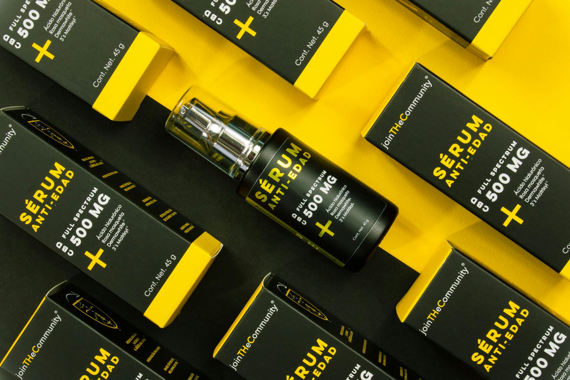 Stylish anti-aging serum packaging with a bold yellow and black color scheme in a flat lay composition.