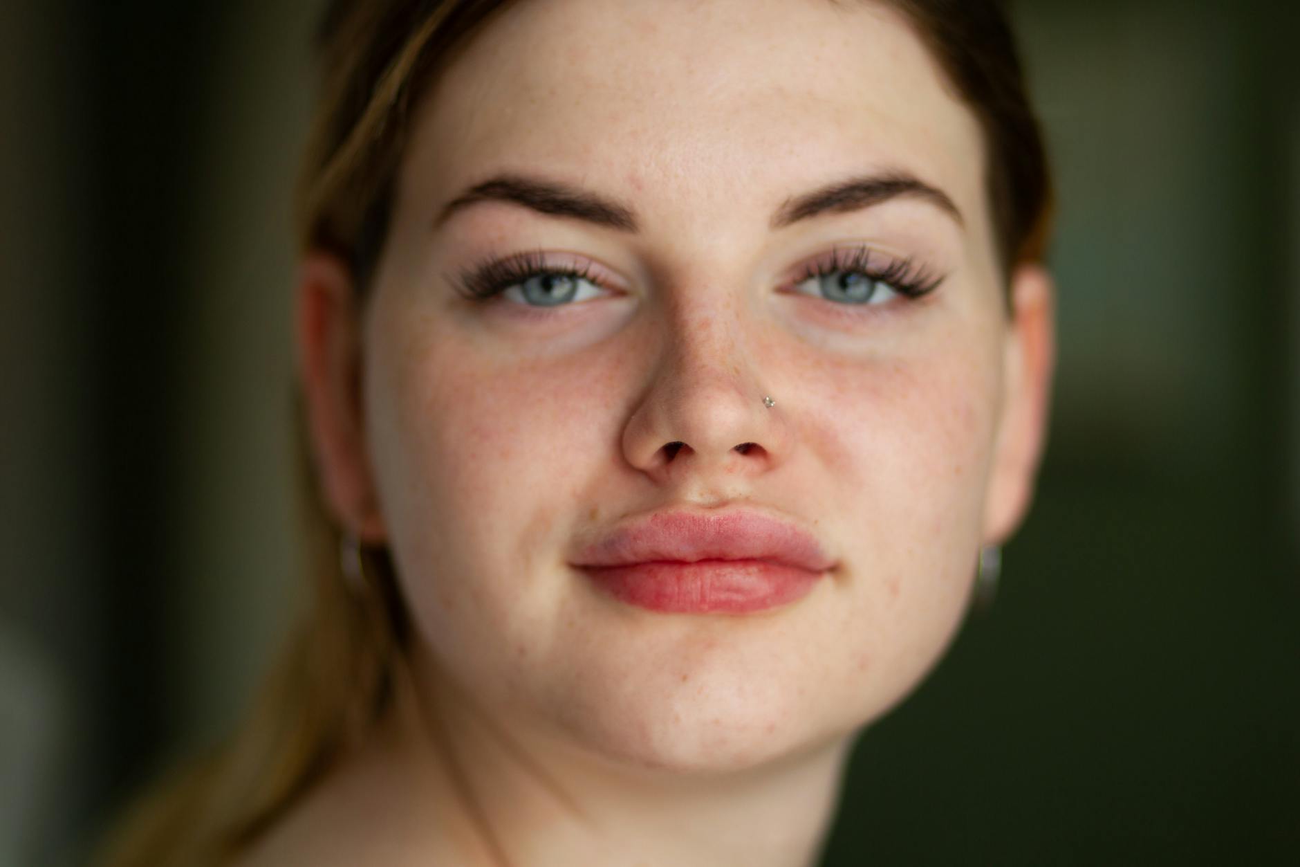Close-up portrait of a young woman with freckles, neutral expression, and natural beauty.