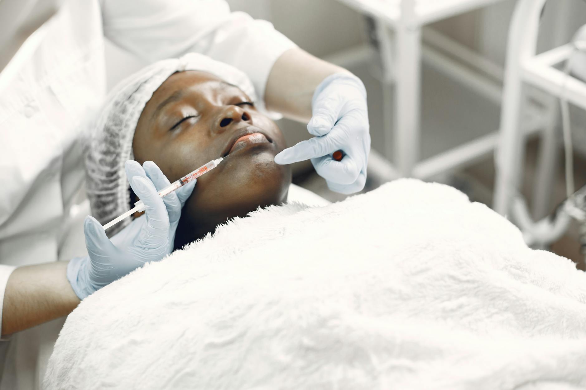 A woman receiving a cosmetic injection with syringe in a medical setting.