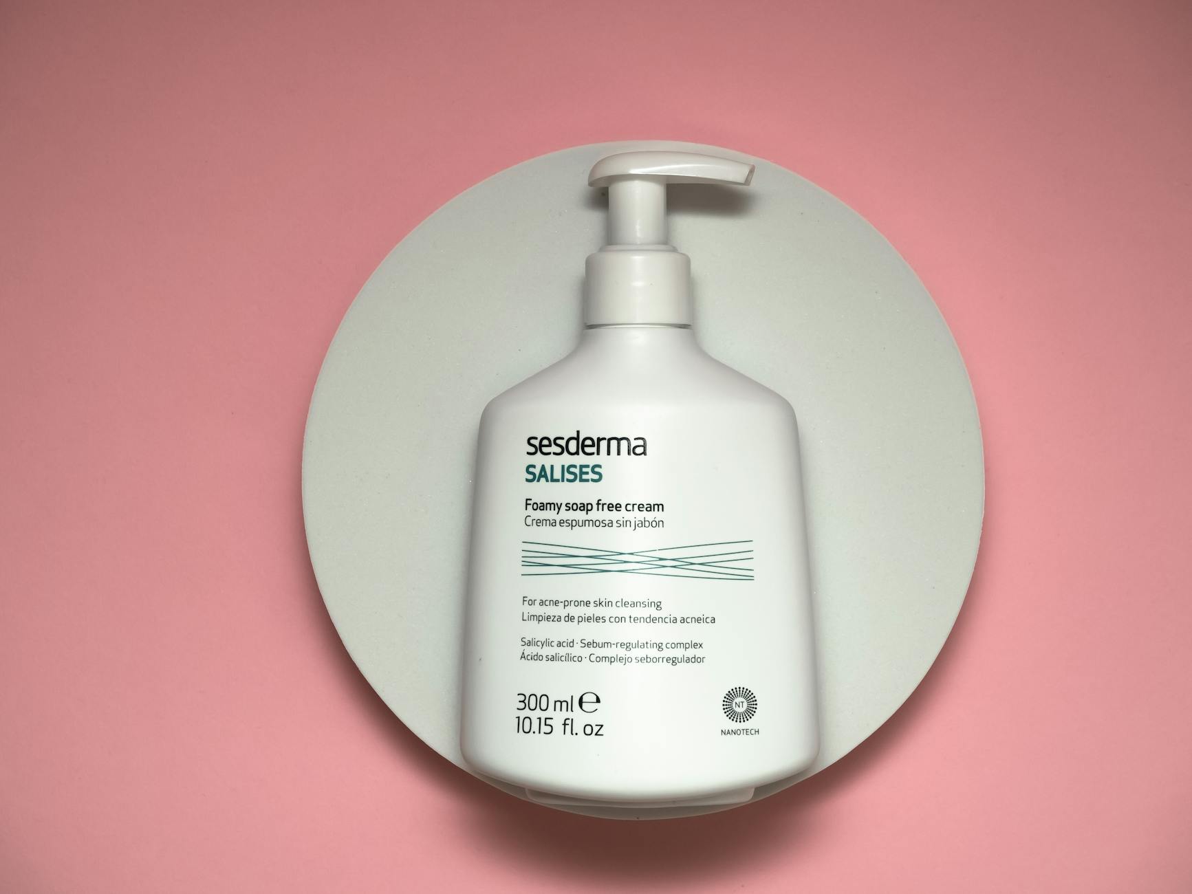 White pump bottle of Sesderma skincare on a pink surface, top view.