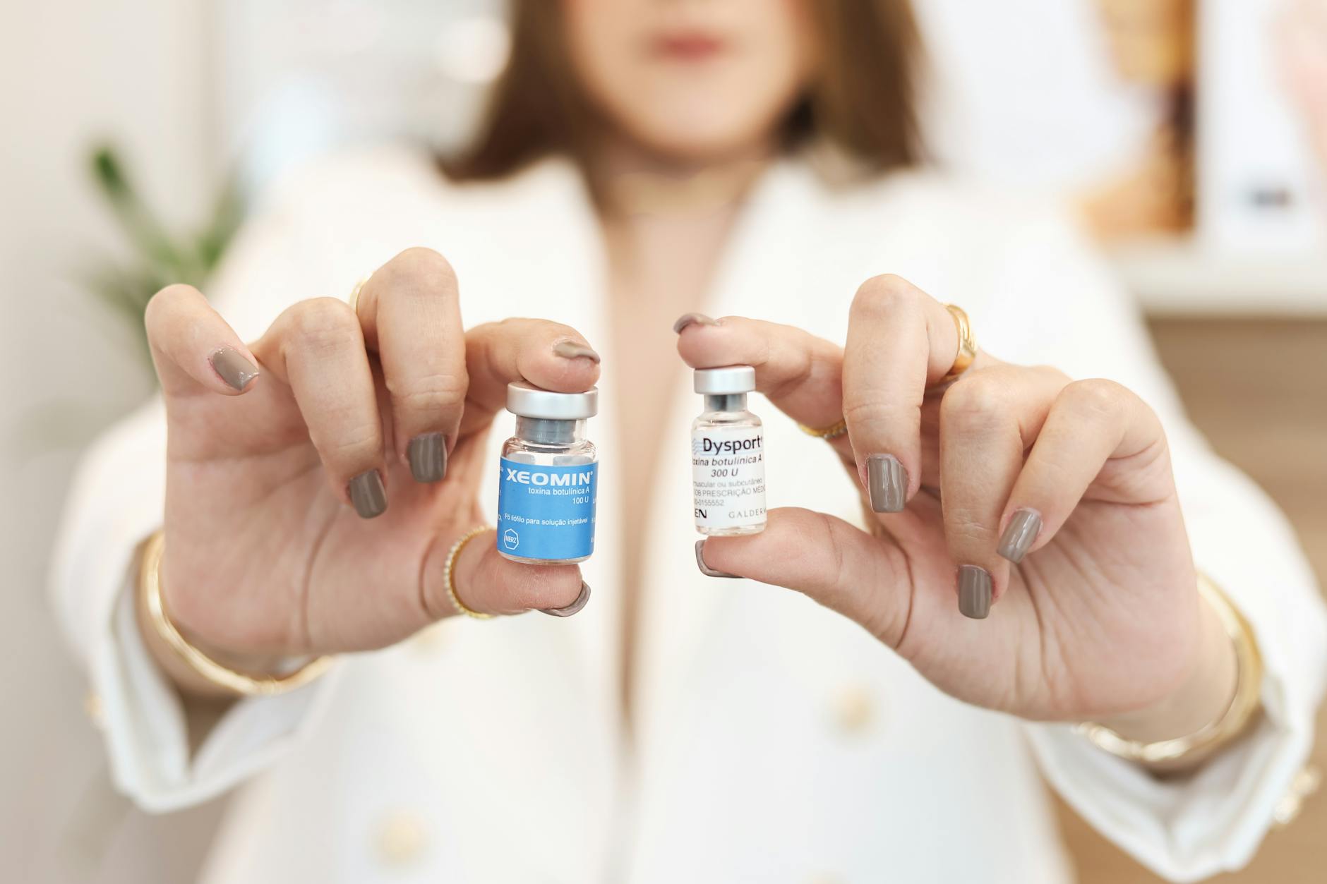 A close-up of a woman holding Xeomin and Dysport vials, showcasing cosmetic treatment options.