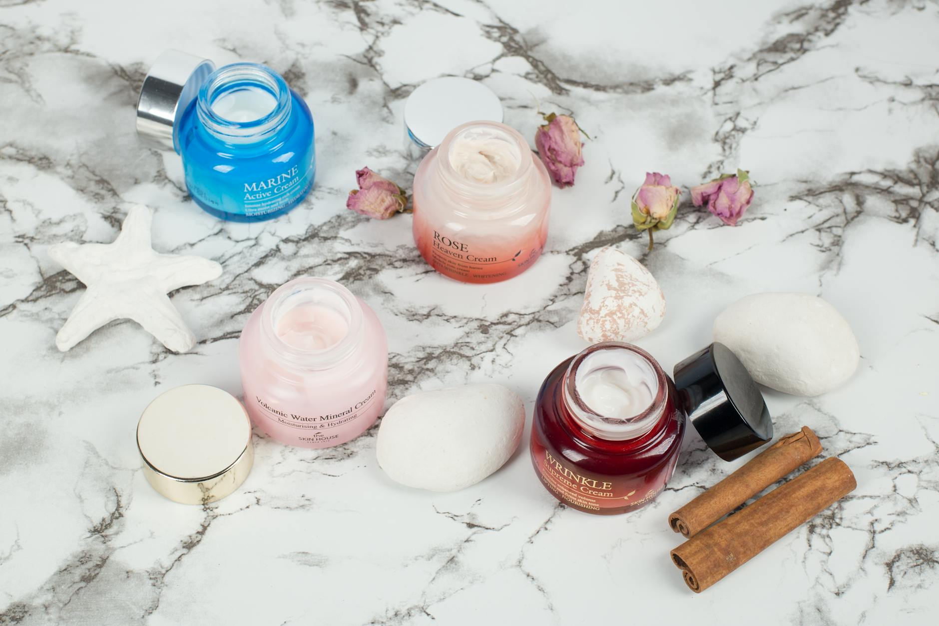 Elegant display of skincare creams with natural elements on a marble surface.